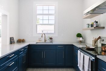 A kitchen with dark blue cabinets and a black stove top oven.